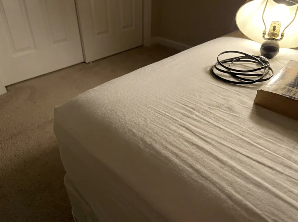 Raking lamplight across white percale showing the one-over-one-under weave grid