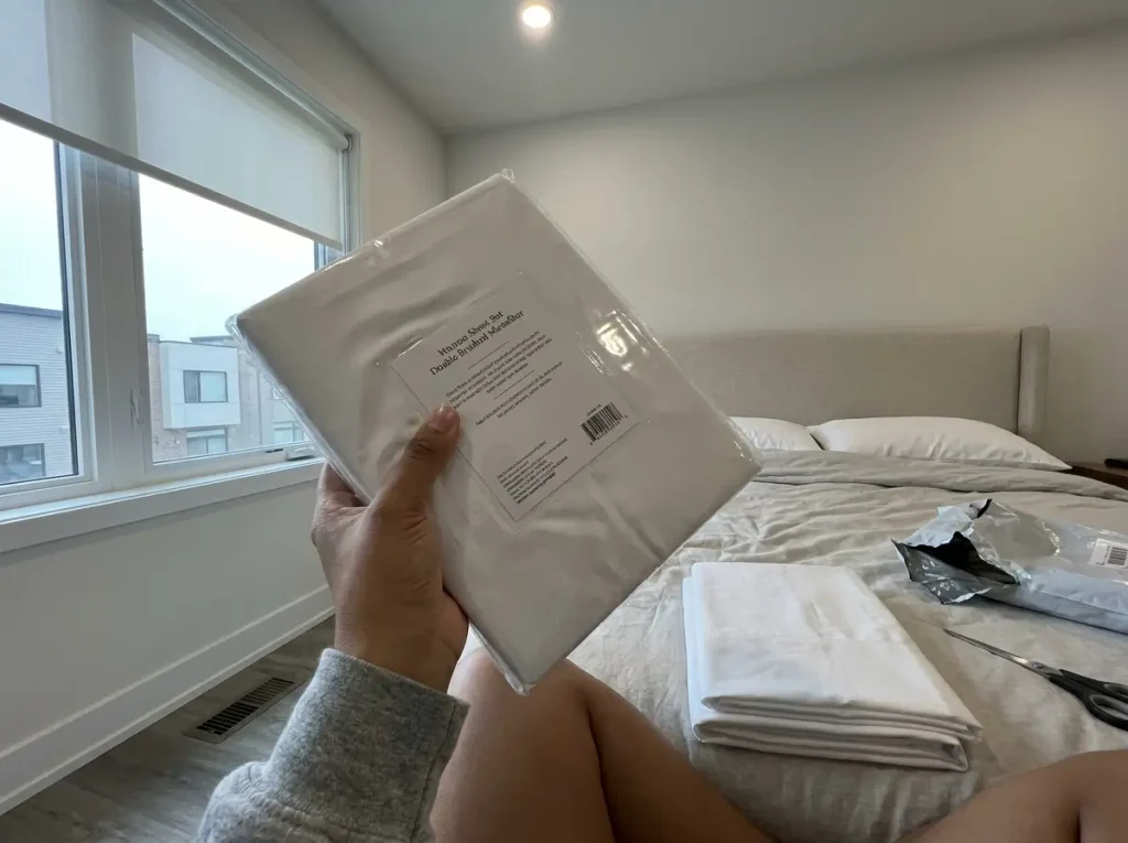 Hands holding a cooling-branded sheet package, turning it to read the fiber content on the back
