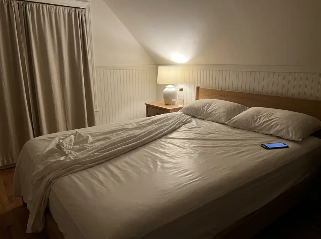 Fitted sheet pulled back at 3 a.m. showing the smooth plastic-backed protector underneath