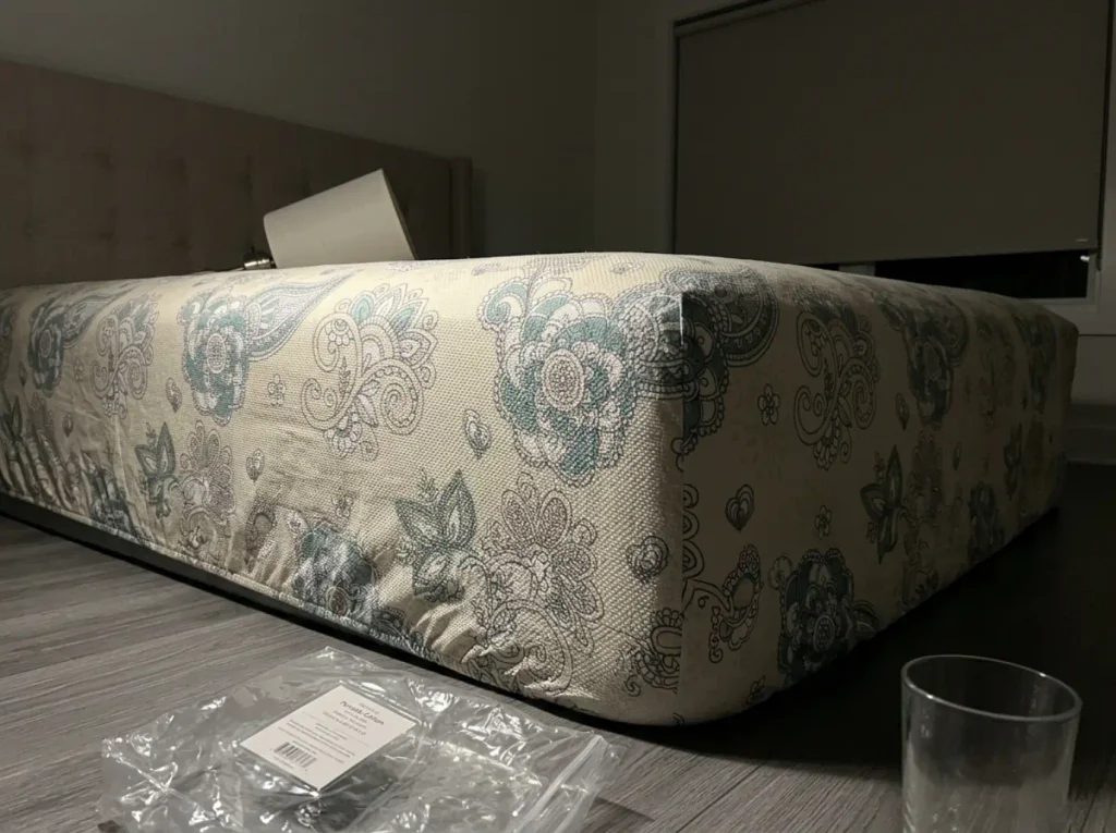 A percale fitted sheet raked by a lamp laid flat, its one-over-one weave grid in tiny shadows