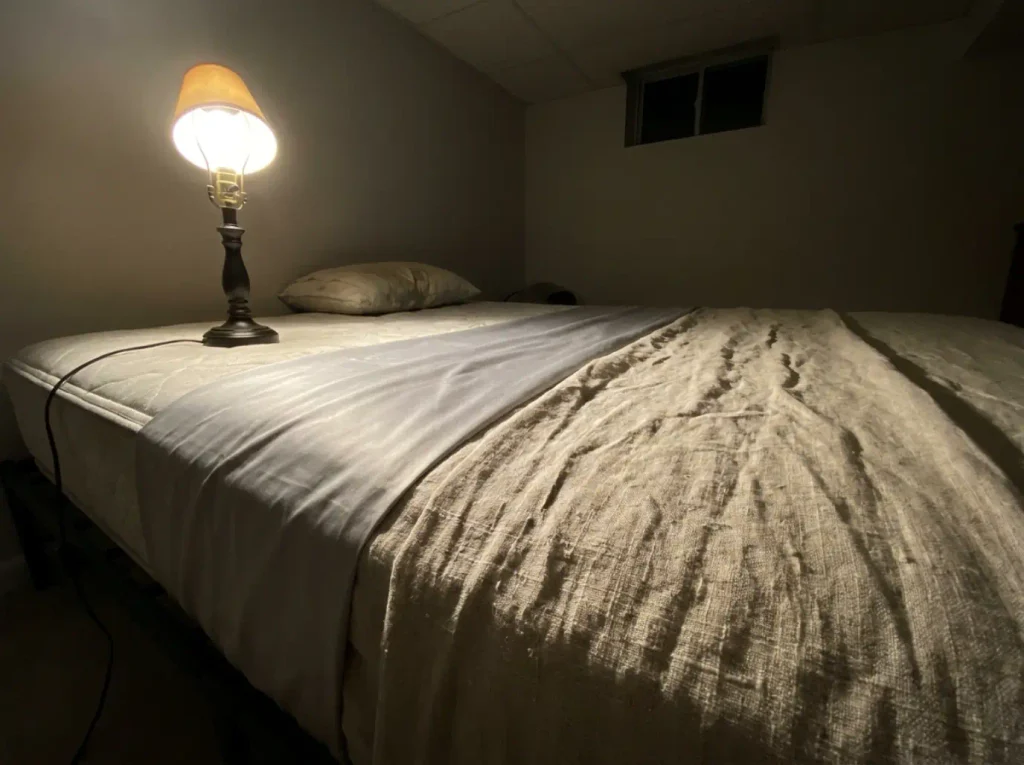Bamboo sateen and linen laid side by side under a raking lamp, one glowing solid and one full of shadows