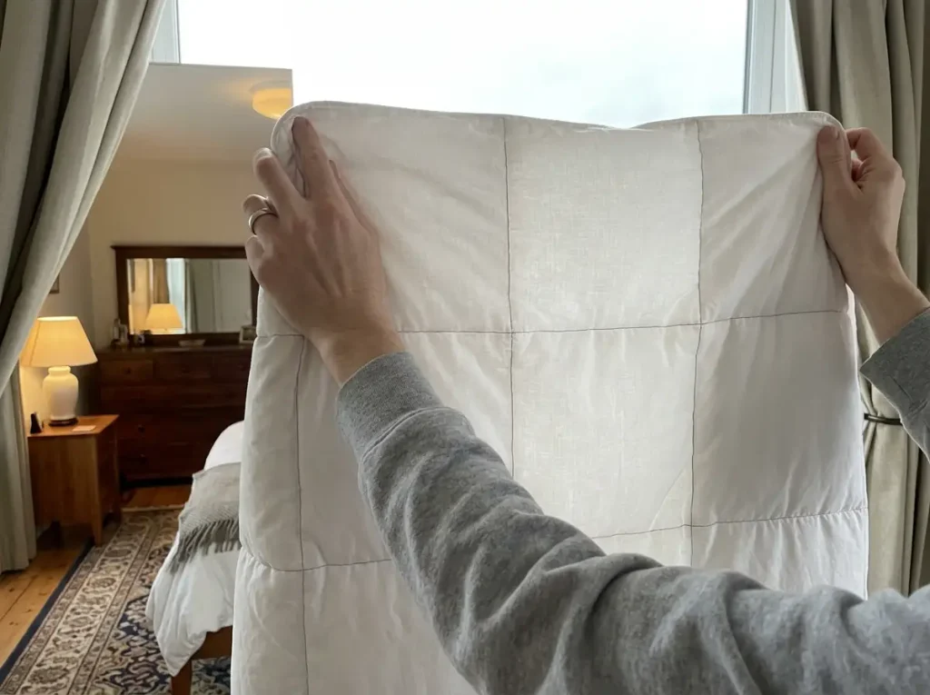 A comforter held up to a bright window so light shows through the thin compartments and not the full ones