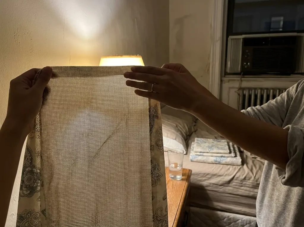 A white cotton percale sheet held up to a lamp showing the grid of its plain weave