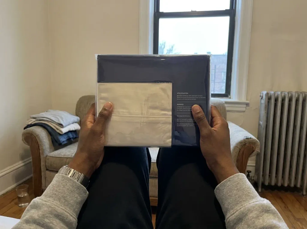 Hands turning a bamboo sheet package over to read the fiber content panel on the back