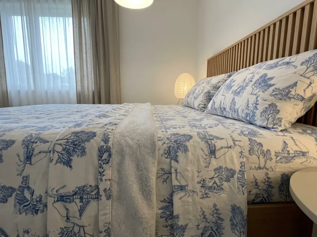 Raking lamplight across a flannel top hem beside a flat percale sheet, showing the nap