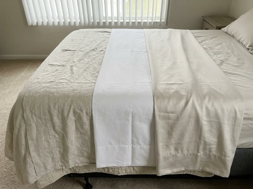 Linen, percale and a smooth sateen sheet laid overlapping to compare texture and drape