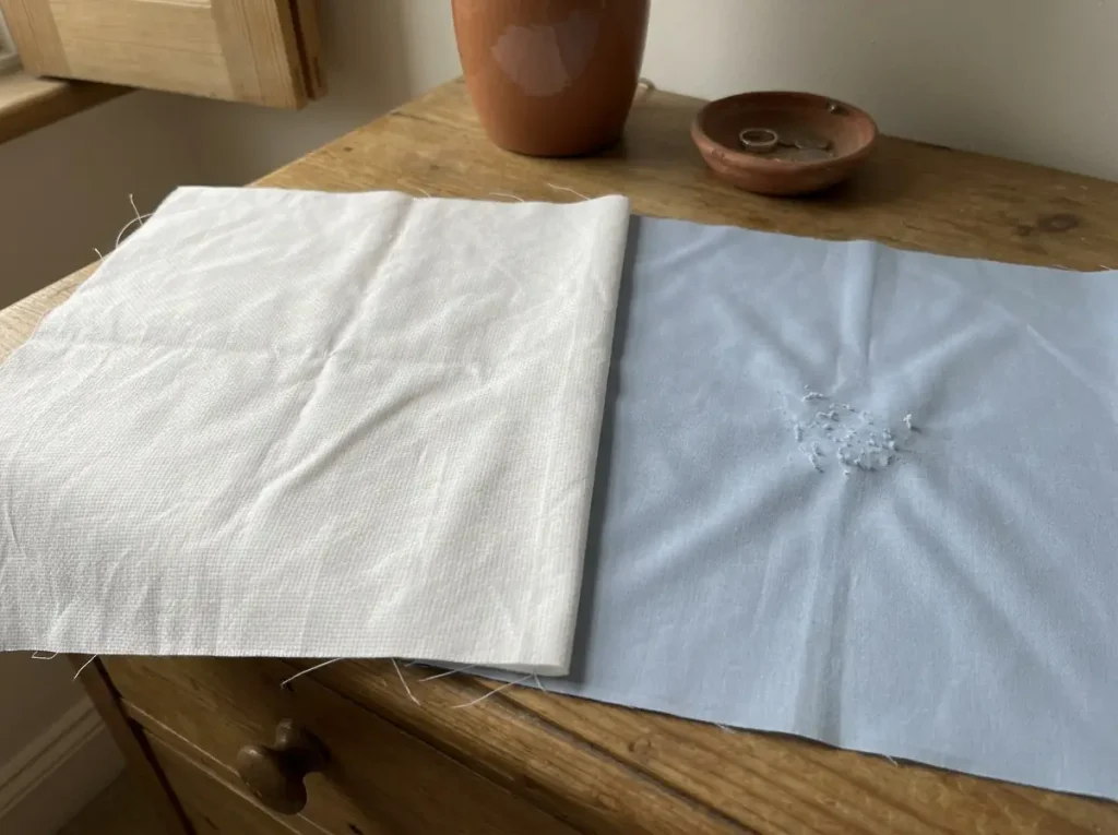 Cotton percale and poly-cotton sheets laid side by side under raking light showing different surfaces
