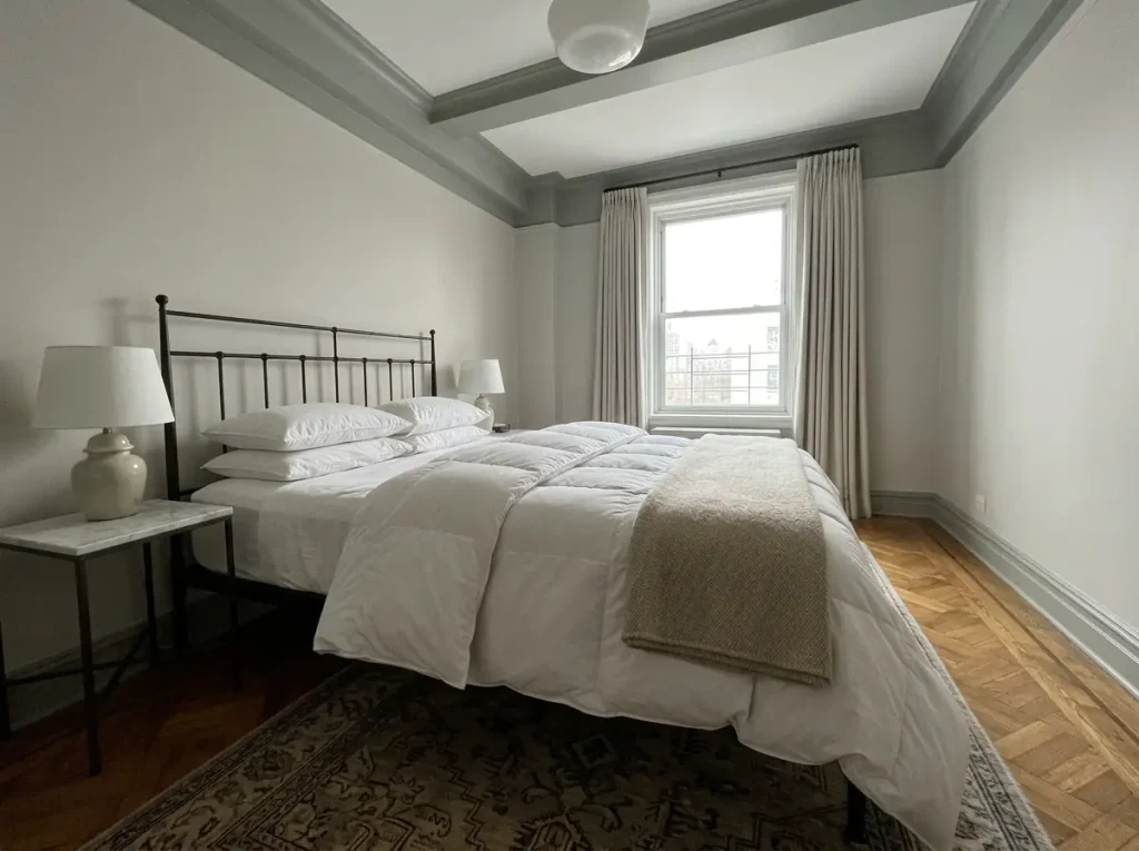 An all-season duvet turned back on the bed with a folded wool blanket beside it, showing the difference in loft