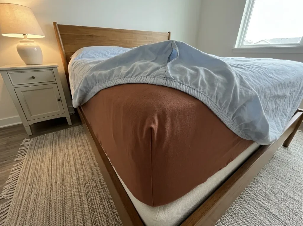Two fitted sheet corners compared on a mattress, one gripping taut and one lifting loose