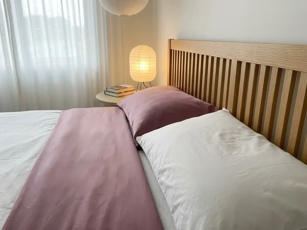 A mulberry silk pillowcase beside a white cotton one at the head of a neatly made bed