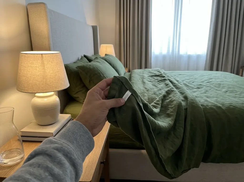 A stonewashed linen sheet set on a nightstand with its sewn-in label turned over under a lamp