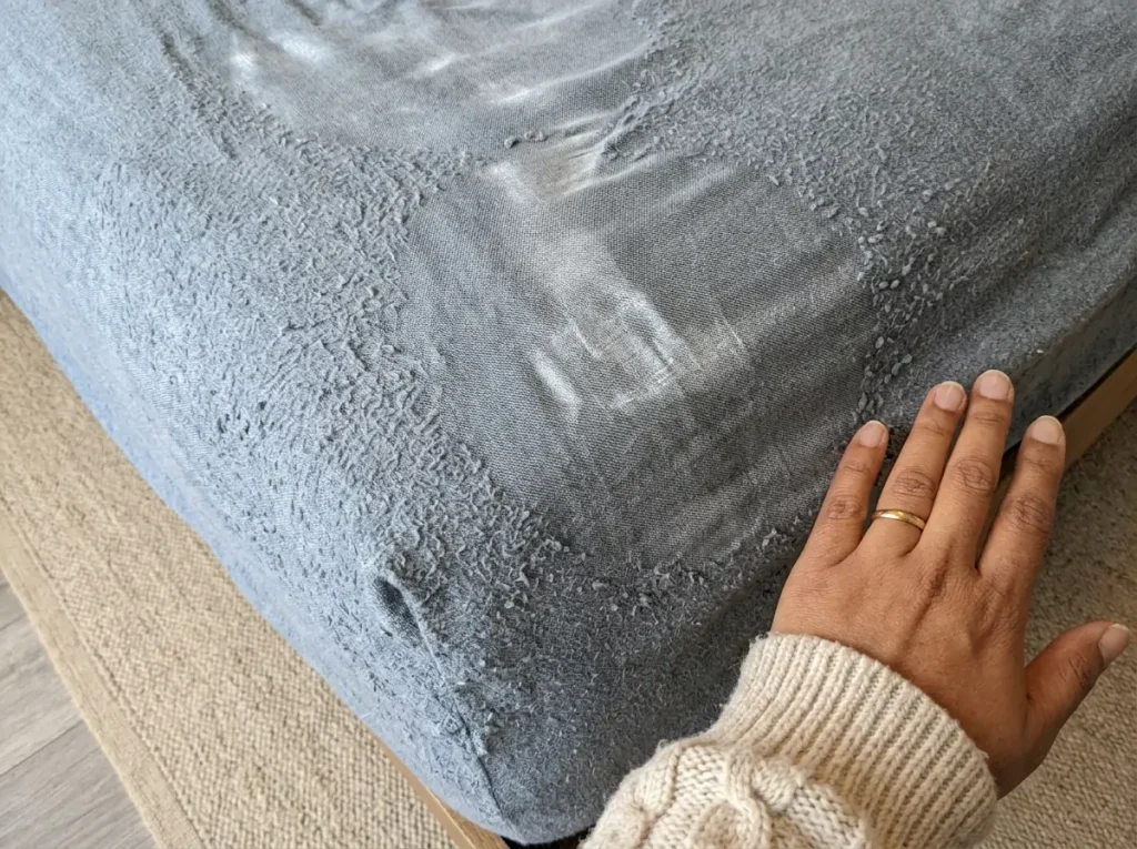 Flat worn patches in the nap at the foot of an old flannel sheet beside its fuzzy areas