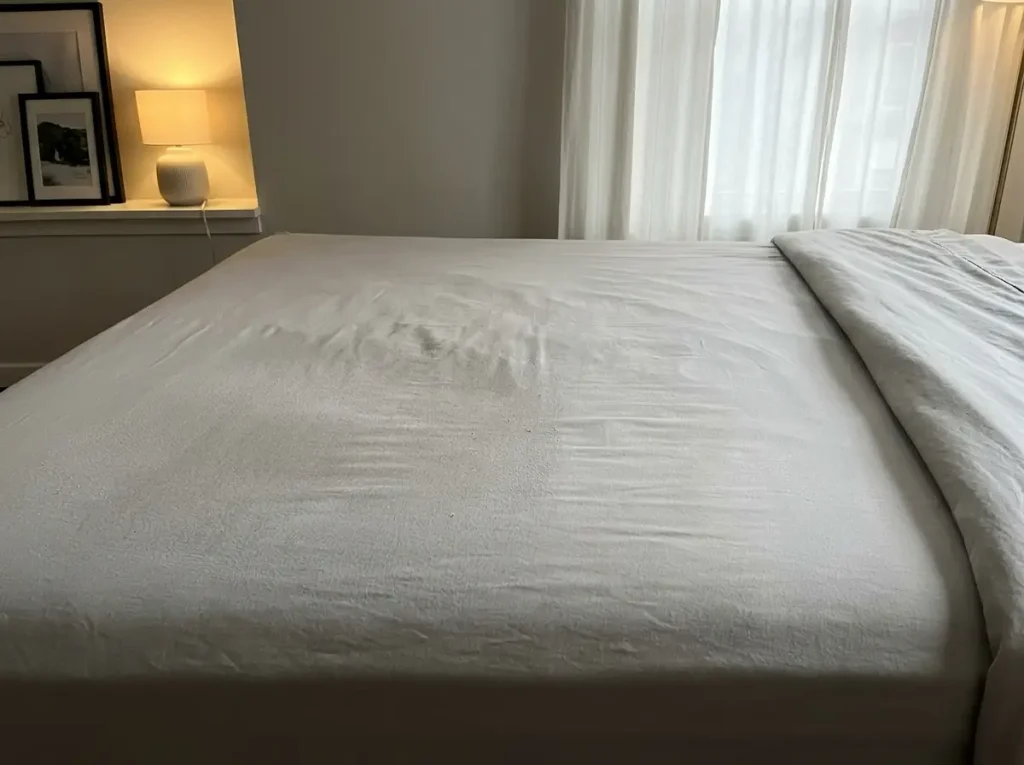 Raking light across a used microfiber fitted sheet showing where the nap has flattened