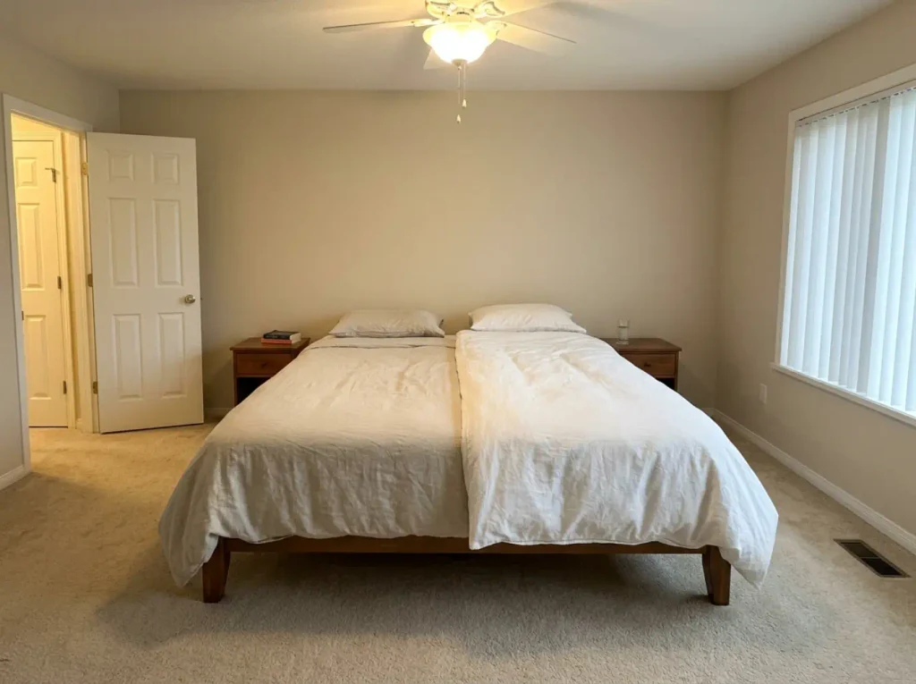 A queen bed made with two separate duvets side by side, one lighter than the other