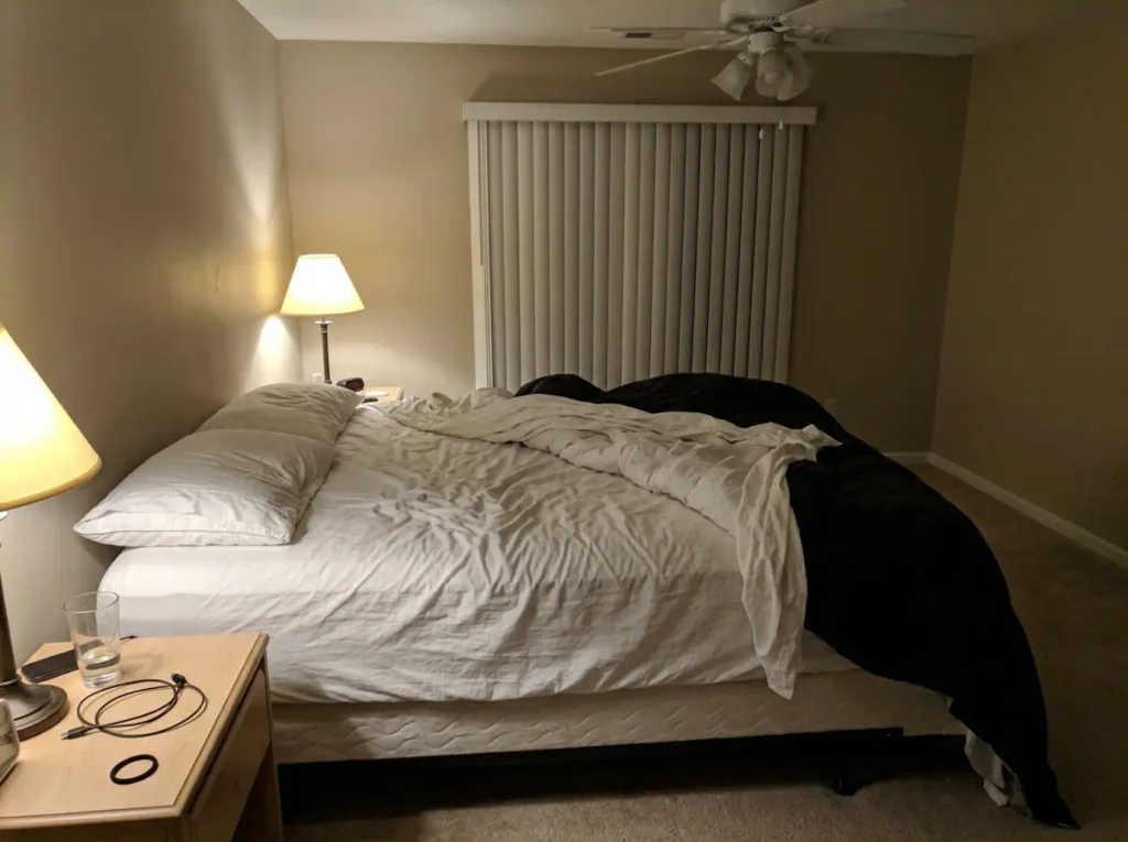 A bed at three in the morning, the sheet twisted to one side and the duvet pushed off