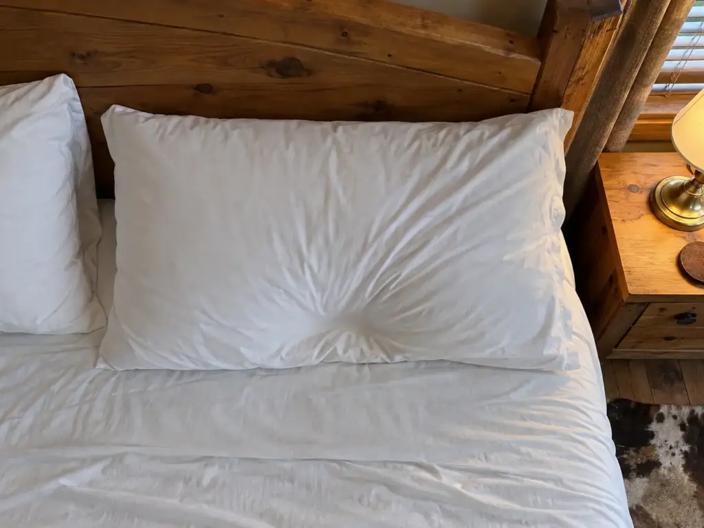 Pillow seen from above with its dent pressed toward one edge and the pillowcase tugged sideways